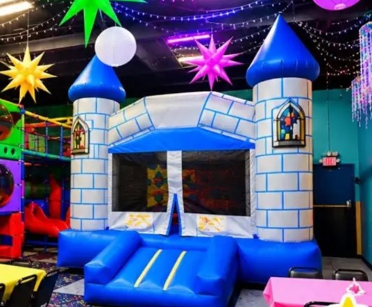 Party Room 2 with a blue and white castle bounce house, a colorful play structure and glowing star decorations